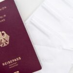 Close-up of a German passport and KN95 masks symbolizing travel during the pandemic.