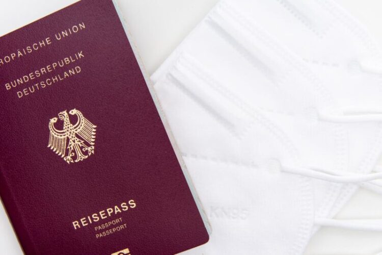 Close-up of a German passport and KN95 masks symbolizing travel during the pandemic.